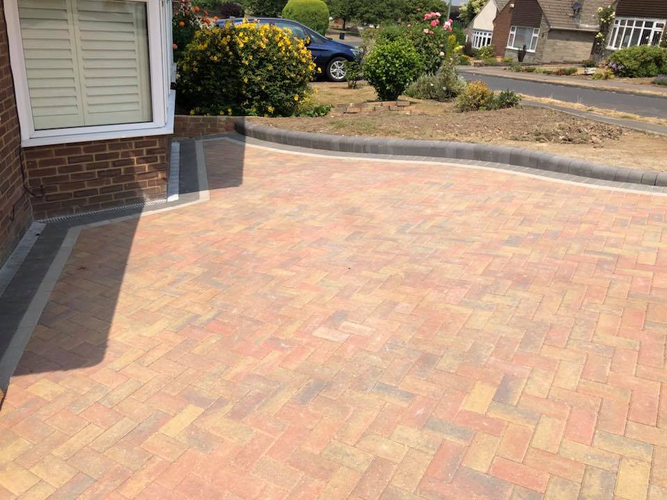 Buff and red block paved driveway with a charcoal curved kerb