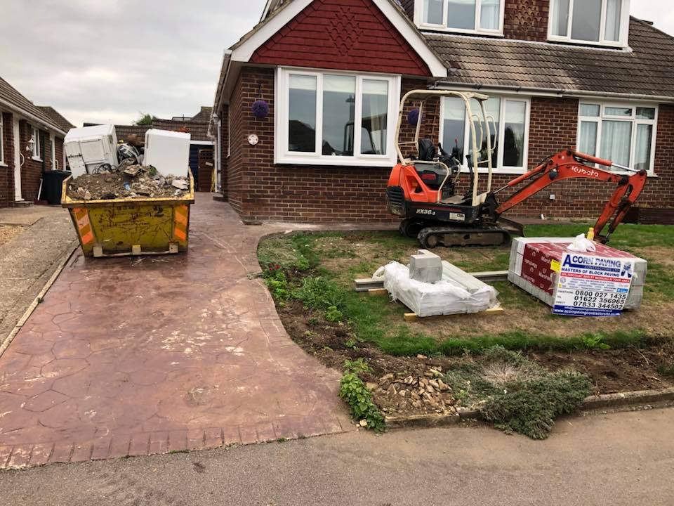 Skip and mini digger removing an old imprinted concrete driveway